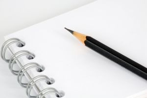Czarny ołówek leżący na pustej kartce notesu na spirali